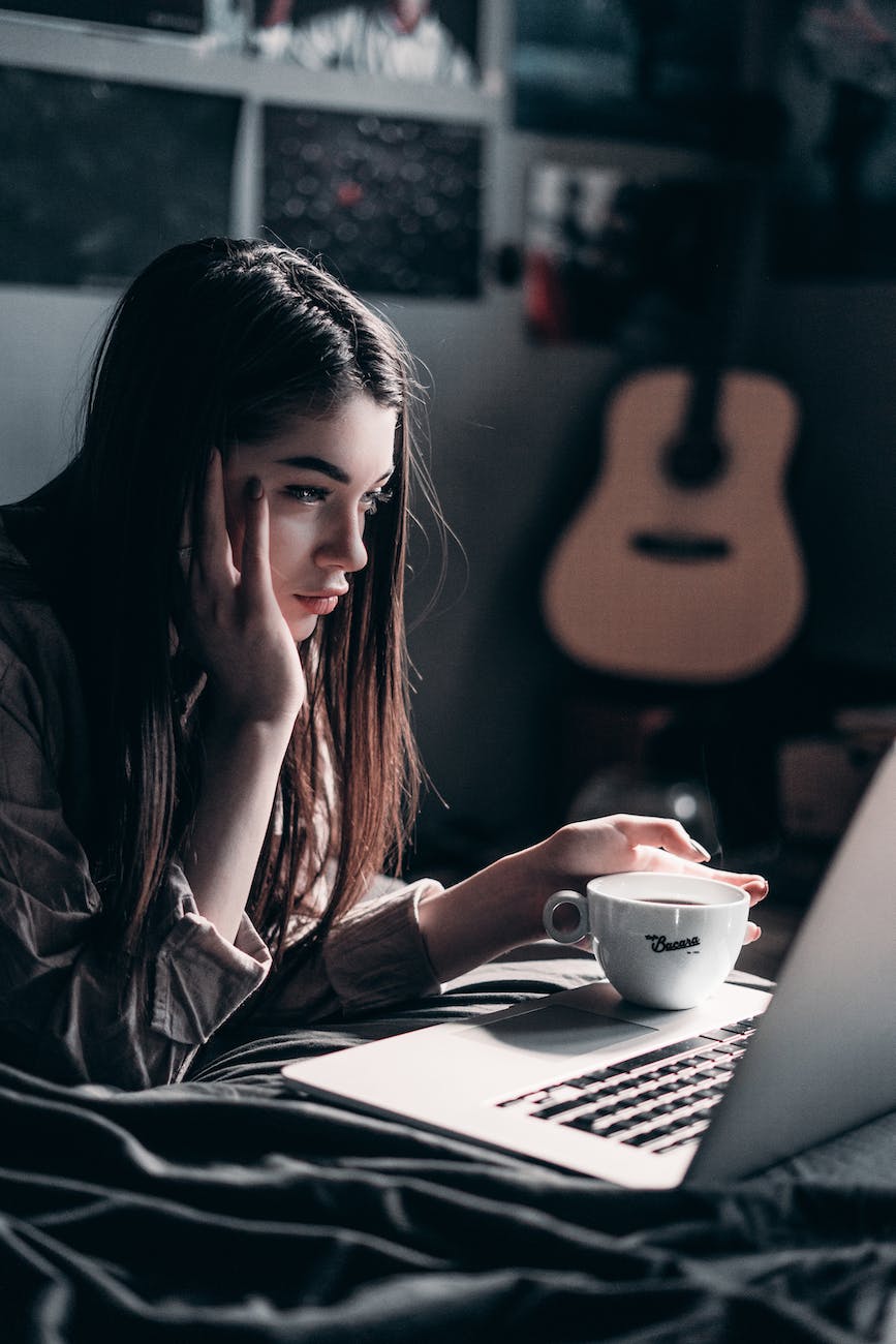 photo of woman lying on bed while using laptop Mac vs coffee spill 