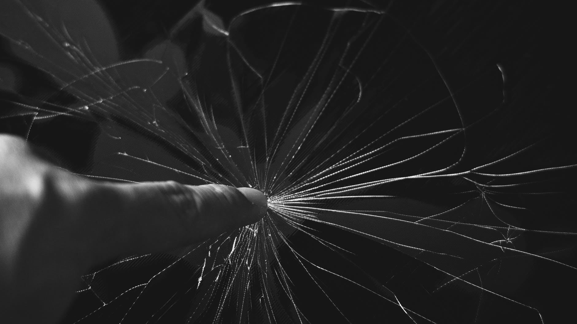 black and white photo of finger touching cracked glass